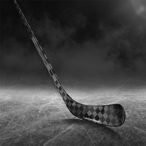 A Pro Stock Blackout carbon fiber hockey stick sitting on black ice.